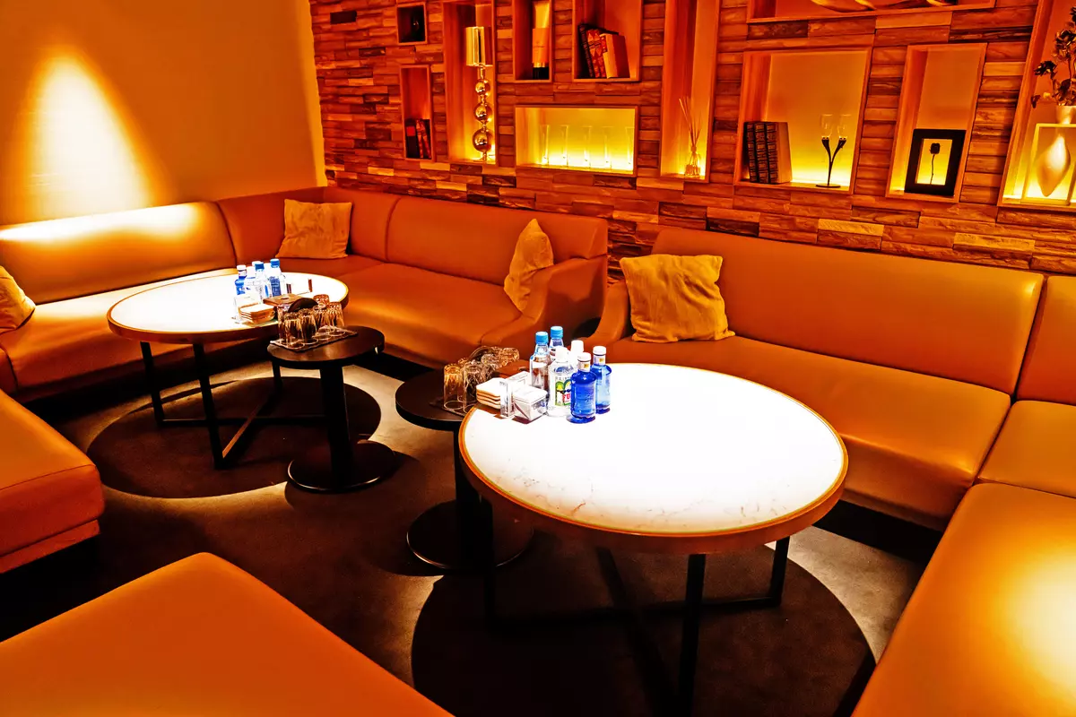 Club Lalah の個室。積層した木の壁とニッチの飾り棚、白く光るテーブル